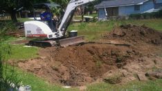 a man is working in the dirt with a small excavator behind him