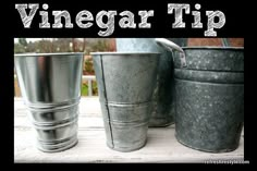 three metal buckets sitting next to each other on top of a wooden table with the words vinegar tip written above them