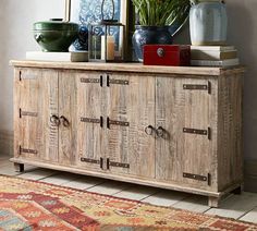 a wooden cabinet with doors and drawers on top of it next to a rug in front of a window