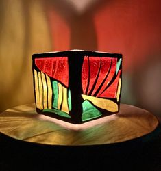 a stained glass candle holder sitting on top of a wooden table