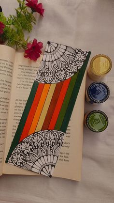 an open book sitting on top of a table next to some flowers and wax bottles