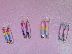 four pairs of colorful beaded earrings hanging from silver hooks on a pink background with glitter