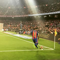 a soccer player is running towards the ball in front of an empty stadium full of people