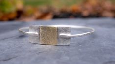 Meet our mixed metal stacking bangle, a long time favorite in our shop and one of the first silver bangle bracelets we created.  This listing is for one bangle, the one you see in most of the photos and video. This "silver and gold" bangle is a great addition to your wrist!  Mix this one in with other bangles for stacking.  Hand made in our studio, this bracelet  is all sterling silver, textured, with a buttery gold brass square.   This bracelet comes in 3 standard sizes. Here is the best way to find your correct bangle size: Using a bangle you own and wear that is comfortable, measure in inches from left to right, the inside diameter at its widest point (the center).   See last photo in this listing for reference.  If using this sizing method: Small Bracelet = 2.25 inches in diameter Medi Unique Bangle Cuff Bracelet For Everyday, Hammered Metal Bangle As Gift, Silver Hammered Brass Bracelets, Hammered Silver Brass Bracelets, Hammered Metal Bangle Gift, Ringwood Nj, Bracelet Stacking, Bangle Silver, Large Bracelet