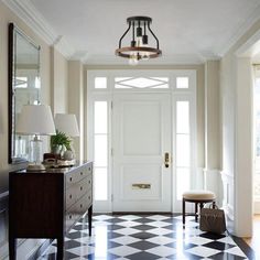 a hallway with black and white checkered flooring, two lamps on either side of the door