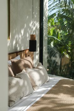 a bed with pillows and lamps on it in front of a window that looks out onto the jungle