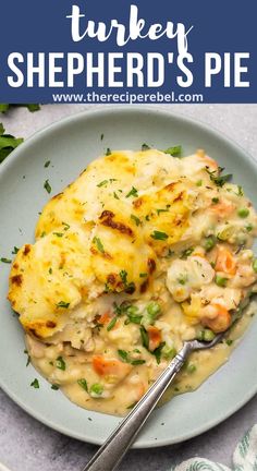 a blue plate topped with chicken and cheese covered in gravy next to a fork