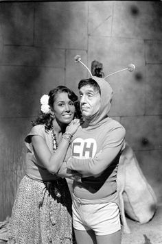 an old black and white photo of a man hugging a woman in front of a stone wall