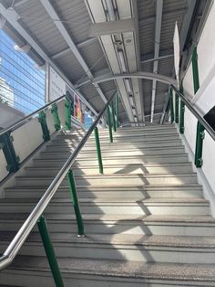 an overhead view of some stairs with green railings and metal handrails in the foreground