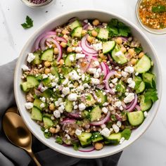 a white bowl filled with cucumber, onions and feta cheese on top of a table