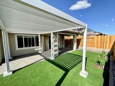 a backyard with grass and a white pergolated roof