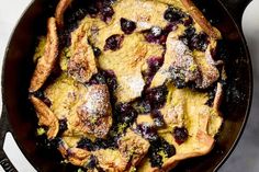 a skillet filled with blueberries and powdered sugar on top of a table