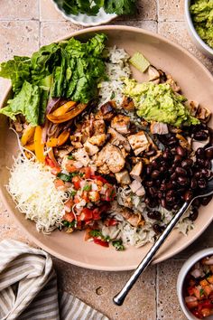 a bowl filled with rice, black beans and chicken next to bowls of guacamole