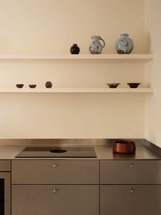 a kitchen counter with some bowls on it and shelves above the stove in front of them