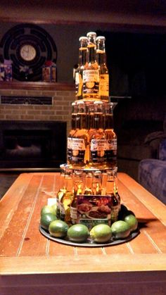 a stack of beer bottles sitting on top of a wooden table next to limes