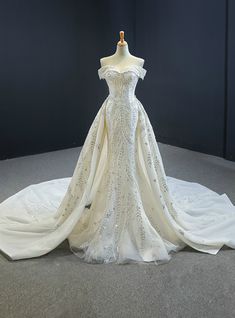 a white wedding dress on display in a room with dark walls and carpeted flooring