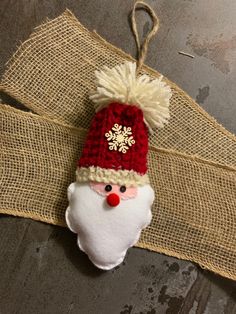 a santa clause ornament hanging on a burlocked piece of fabric