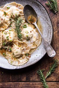 a white plate topped with dumplings covered in gravy next to a spoon