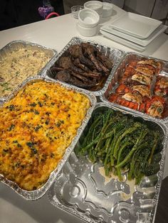 four trays filled with different types of food on top of a white tablecloth