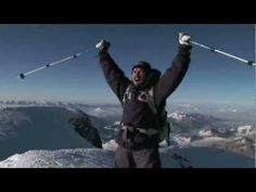 a man standing on top of a snow covered mountain holding skis in the air