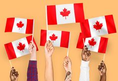 several people holding canadian flags in the air with their hands up and fingers on them