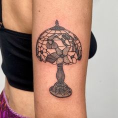 a woman's arm with a tattoo on it that has a stained glass lamp