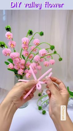 a person is making a flower arrangement out of fake pink flowers with scissors and thread