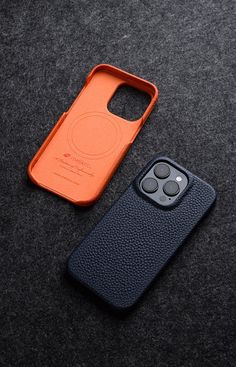 an orange and black case sitting next to a cell phone on a gray surface,