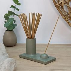 two vases with sticks sticking out of them on a table next to a potted plant