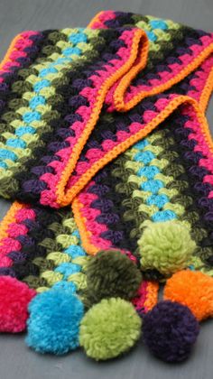 multicolored crocheted afghans with pom - poms laid out on the floor