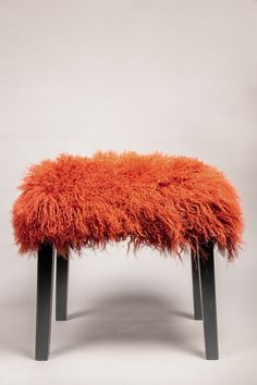 an orange bench with black legs and fur on it