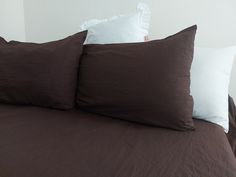 two brown pillows sitting on top of a bed next to each other with white pillows