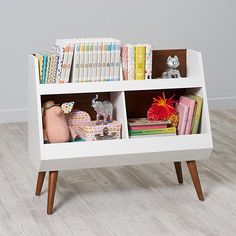 a white book shelf with books and toys in it on top of a hard wood floor