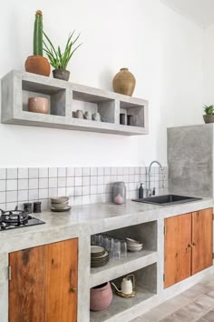 a kitchen with wooden cabinets and white tile on the wall, potted plants above the sink