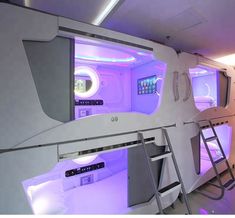 the interior of an airplane is lit up with purple lights and features bunk beds that are built into the ceiling