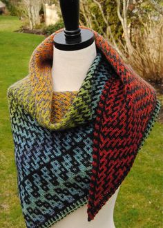 a close up of a mannequin wearing a multicolored knitted shawl