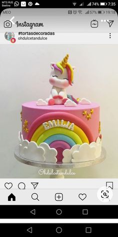 a pink cake with a rainbow and unicorn on top