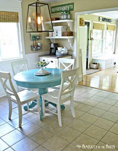 a blue table with white chairs in a kitchen next to a doorway and window on the wall