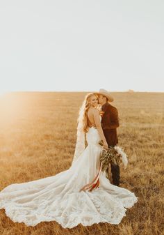 a bride and groom are standing in the middle of an open field with tall grass