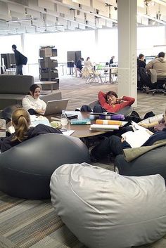 group of people sitting on bean bags in an office building with tables and chairs around them