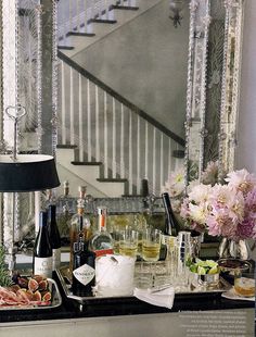 a table topped with lots of food and drinks next to a stair case filled with flowers