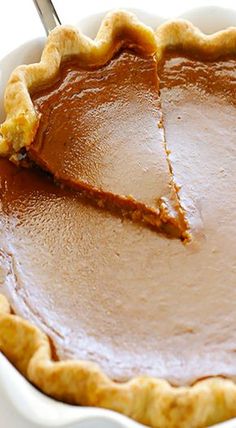 a pie with a slice taken out of it sitting in a white dish on a table