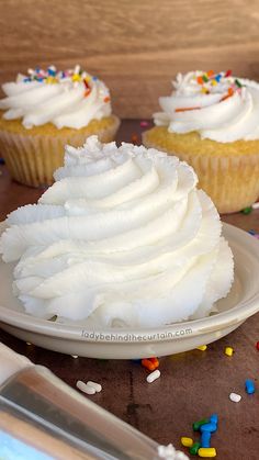 cupcakes with white frosting and sprinkles on a plate