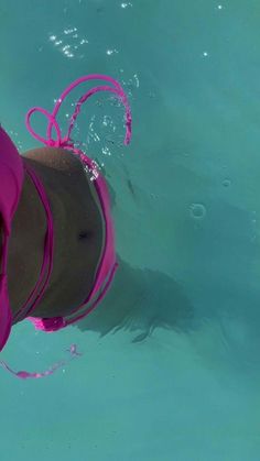 a woman wearing a pink hat and swimming in the water with her hands on her hips