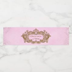 a pink and gold ticket with the words once upon princess on it, sitting on a marble surface