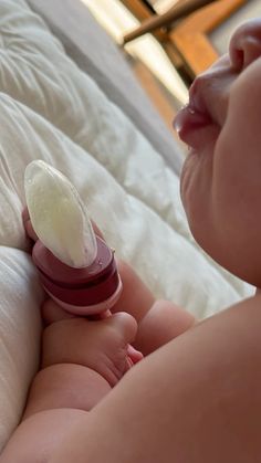 a baby laying on top of a bed with a bottle in it's mouth