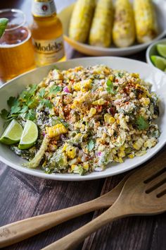 a plate full of mexican food next to some corn on the cob and lime wedges