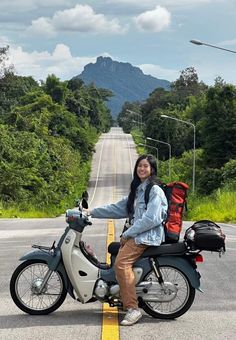 a woman is sitting on a scooter in the middle of an empty road