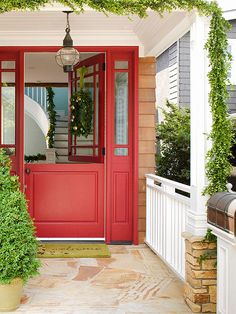 a red front door with potted plants on the porch