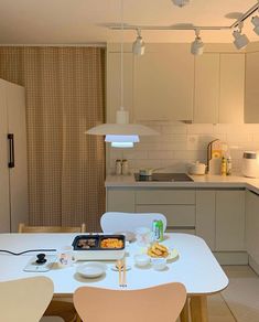 a white table and chairs in a small room with an oven on the far wall